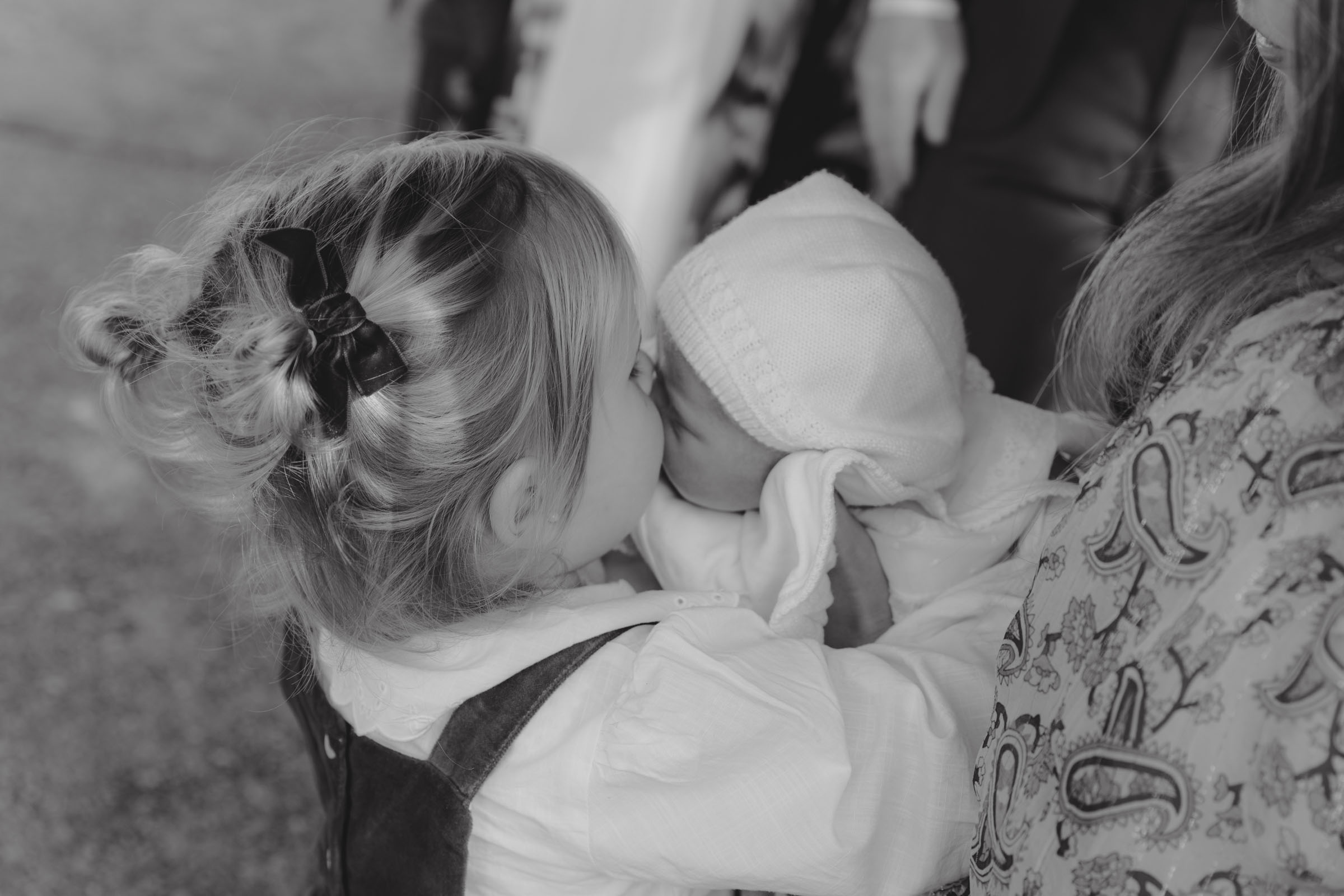 sisters kissing each other during a family session in the retiro park of madrid, spain